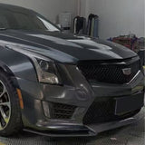 A close-up of the front left side of a dark gray Cadillac in a garage, showcasing its headlight, Cadillac grille, sleek lines, and Sparkle Black Matte SelfRepair Nano-Coated Nexthor™ for superior protection.