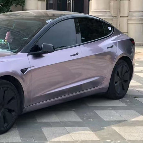 A purple Tesla sedan wrapped in Nexthor Sunshine Purple Liquid Metallic Matte SelfRepair Nano-Coated PPF is parked on stone tiles in front of a building with decorative stone columns and walls.
