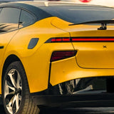 A close-up of the rear and side of a yellow electric car wrapped in Racing Yellow Glossy SelfRepair Nano-Coated PPF, showcasing sleek lines, a continuous red tail light, black trim accents, and modern alloy wheels.
