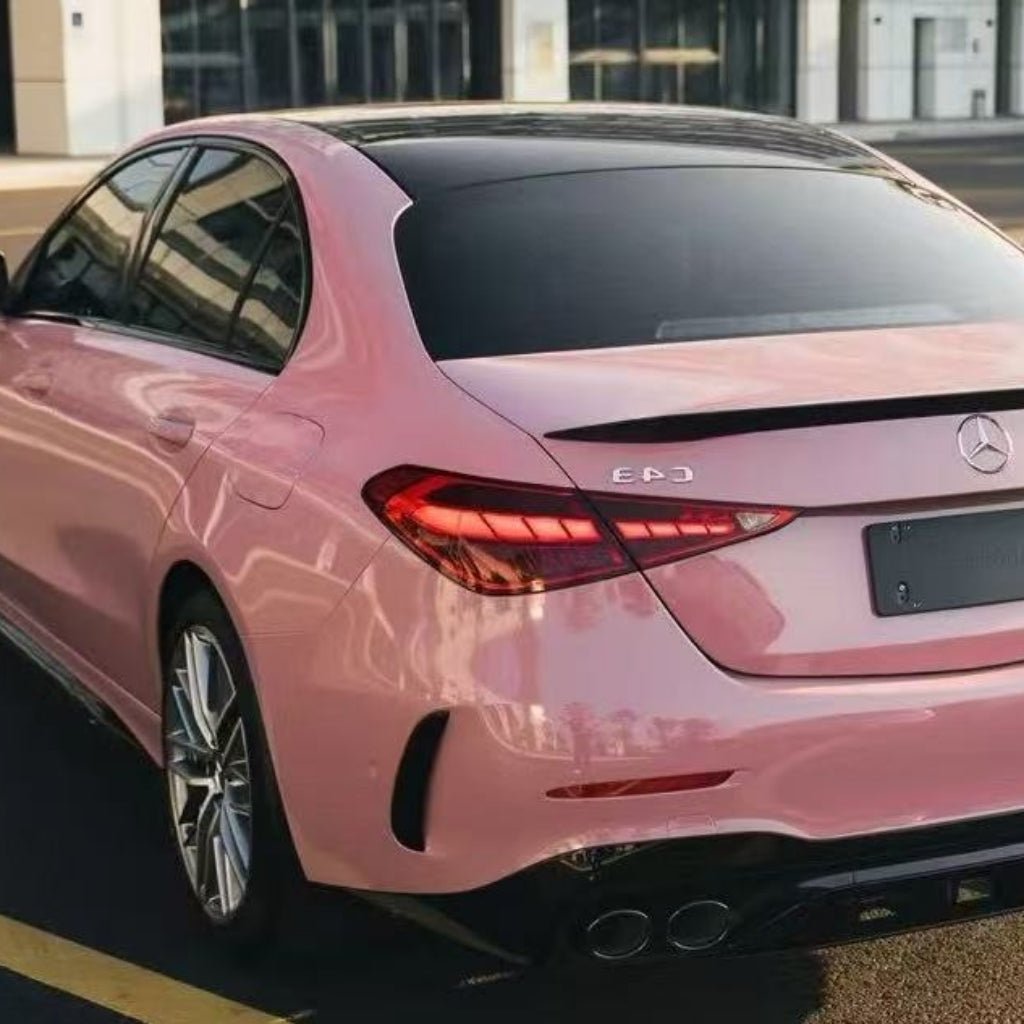 A Mercedes-Benz E-Class sedan in Rouge Pink Glossy SelfRepair Nano-Coated PPF, seen from the rear left, features tinted windows and a black spoiler. The PPF provides a durable protective barrier for the vehicle.
