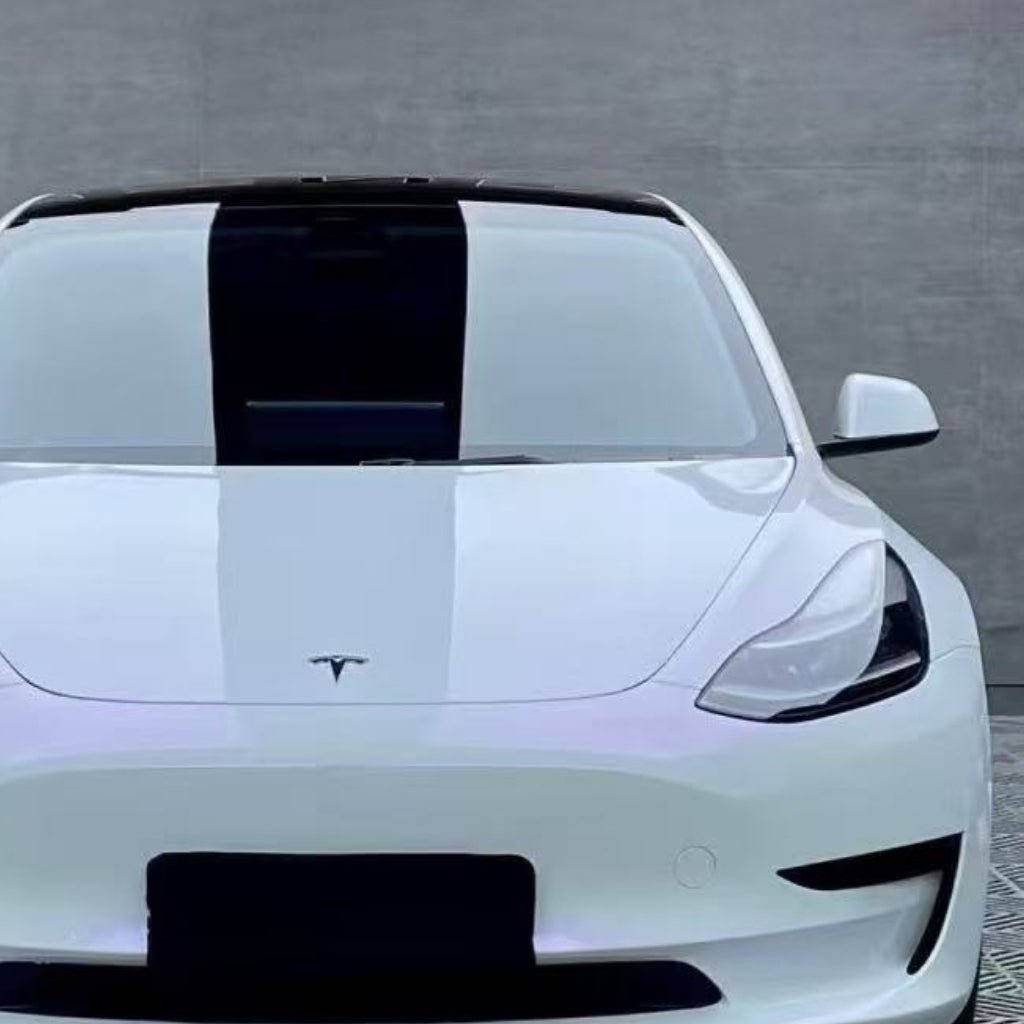 A white Tesla with a black racing stripe, protected by White Diamond Purple Glossy SelfRepair Nano-Coated PPF, is parked in front of a plain concrete wall.