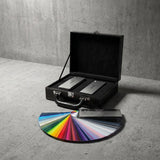 An open Nexthor PPF Sample Kit (All Colors) with two metal boxes sits on concrete, showcasing a fanned-out color swatch featuring a wide range of vibrant and neutral paint colors.